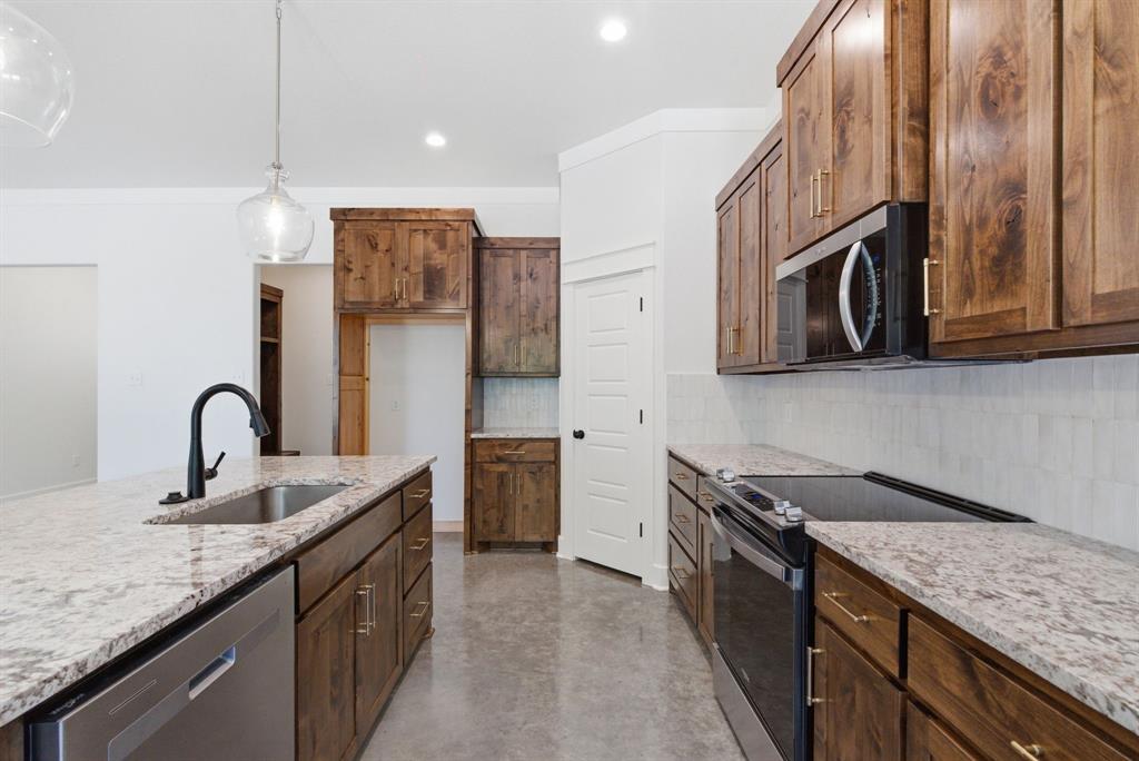 109 Graystone Weatherford, TX 76088 - Photo 6 of 26 a kitchen with stainless steel appliances granite countertop a sink a stove and a wooden cabinets