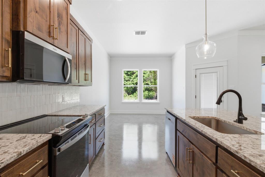 109 Graystone Weatherford, TX 76088 - Photo 7 of 26 a kitchen with stainless steel appliances granite countertop a sink dishwasher a stove and a microwave with wooden floor