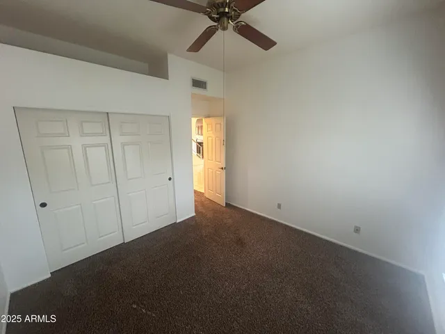 an empty room with windows and fan