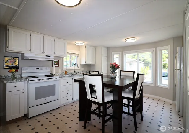 a kitchen with stainless steel appliances a table chairs sink and cabinets