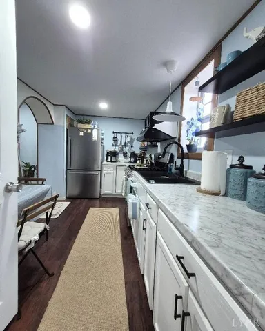 a kitchen with kitchen island a counter top space a sink a refrigerator and cabinets