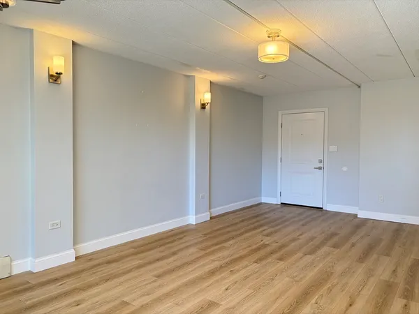 a view of an empty room with wooden floor and windows