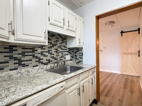 a kitchen with granite countertop a sink and a wooden floor