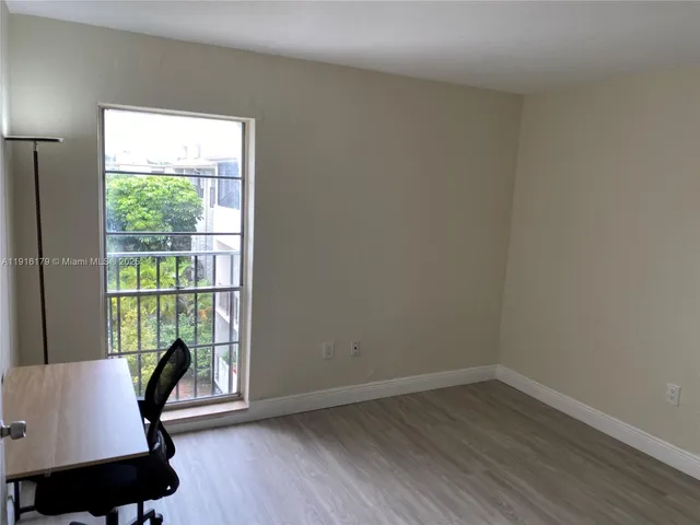 a view of a workspace with wooden floor and a window