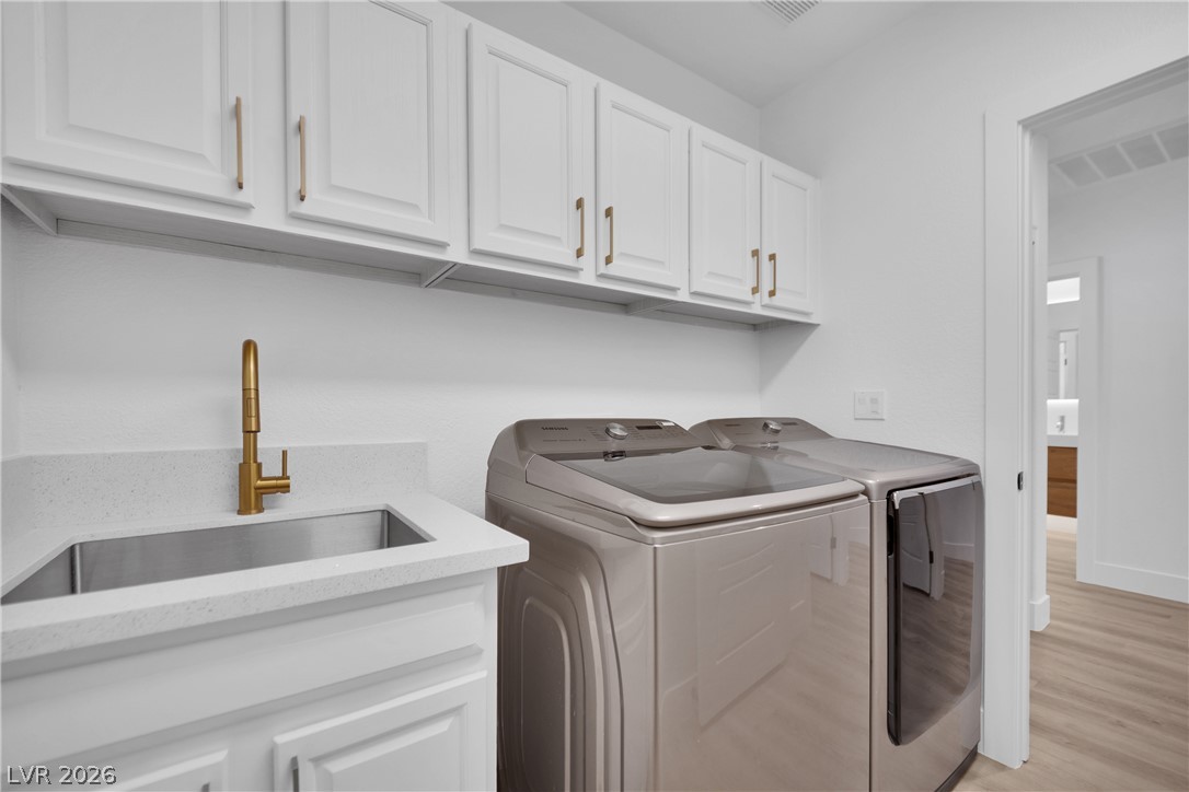 8981 Rivers Edge Drive Las Vegas, NV 89117 - Photo 28 of 69 Functional laundry space featuring modern appliances, crisp white cabinetry, and a convenient sink for everyday tasks.