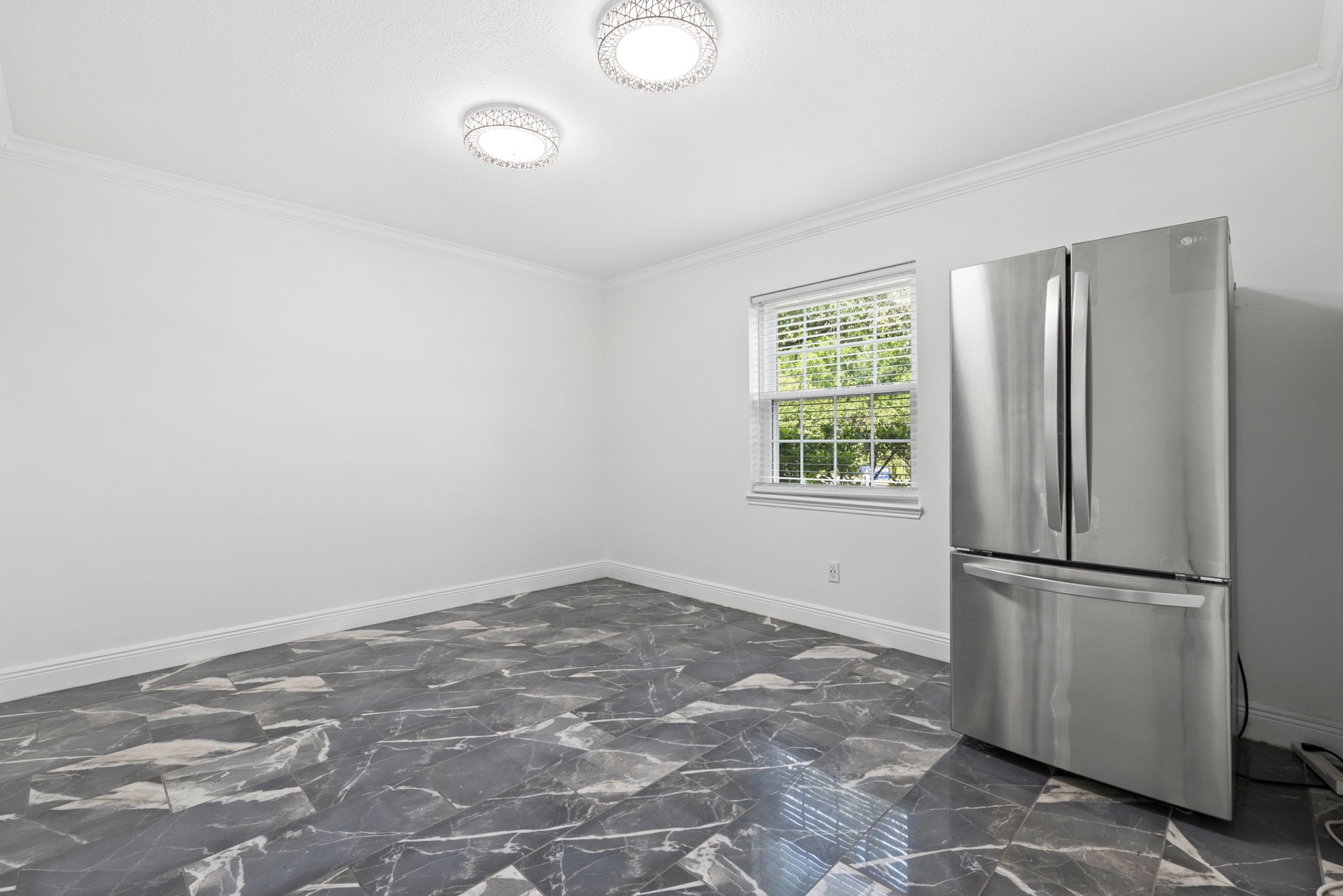 7900 Westheimer Road, Unit 121 Houston, TX 77063 - Photo 15 of 23 Bright, modern space with sleek tile flooring and a stainless steel refrigerator, ideal for creating a welcoming kitchen or dining area.