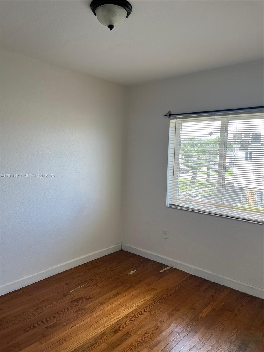 403 Northwest 84th Street, Unit 403 Miami, FL 33150 - Photo 5 of 5 a view of an empty room with wooden floor and a window