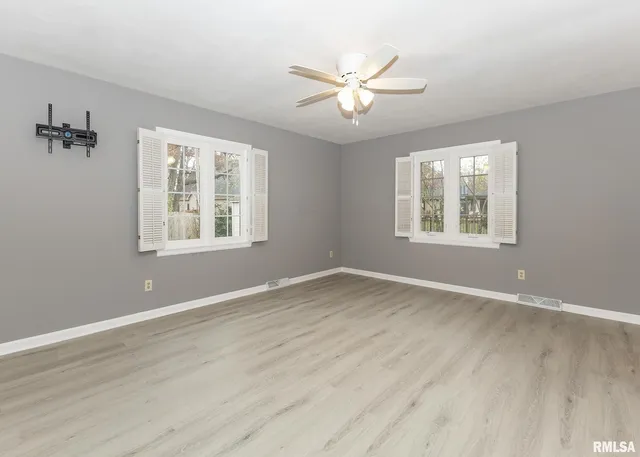 a view of an empty room with a window and wooden floor