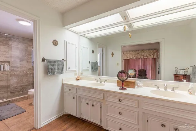 a spacious bathroom with double sink a mirror and shower