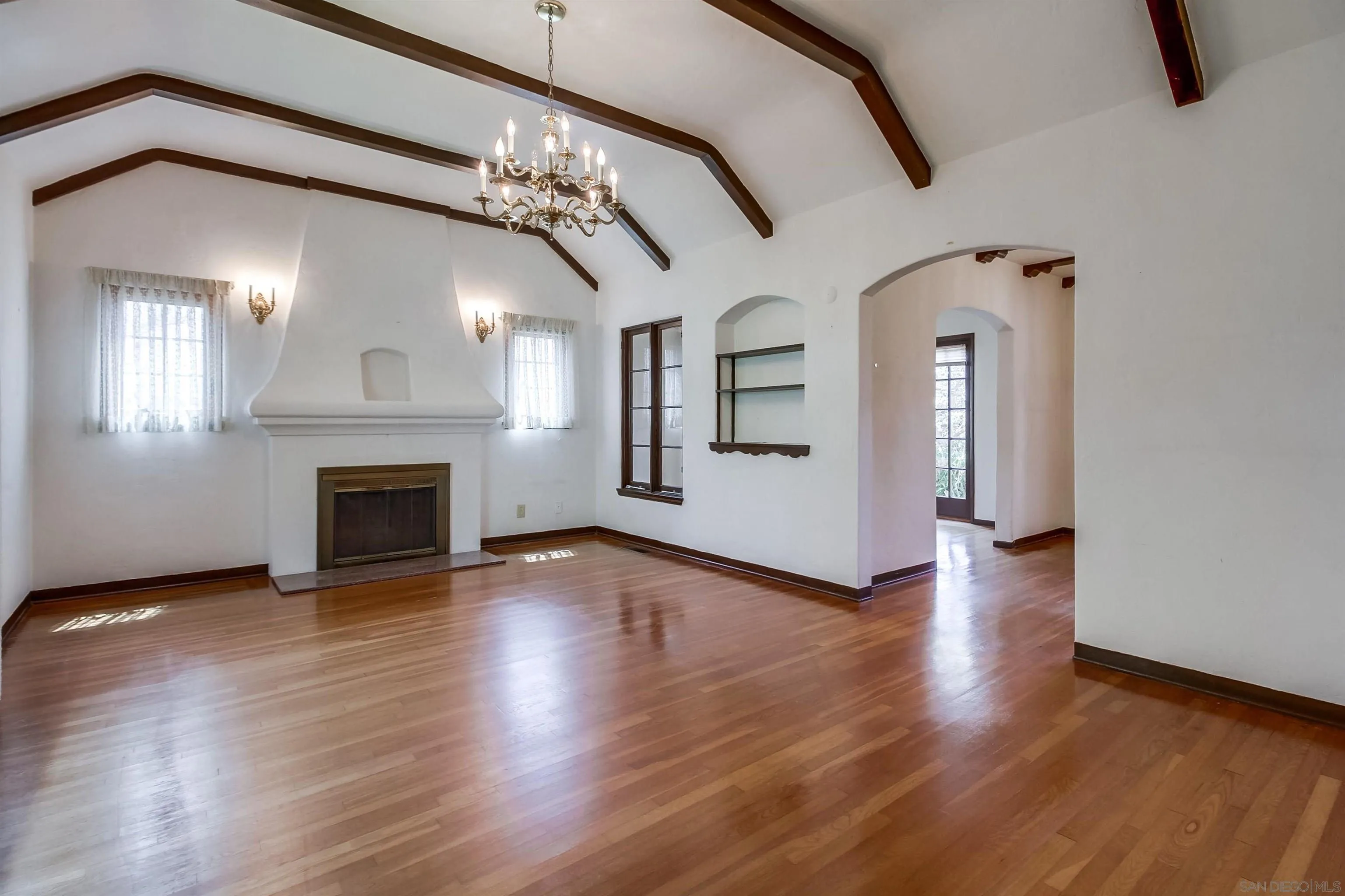 340 B Avenue Coronado, CA 92118 - Photo 6 of 31 an empty room with wooden floor chandelier and fireplace