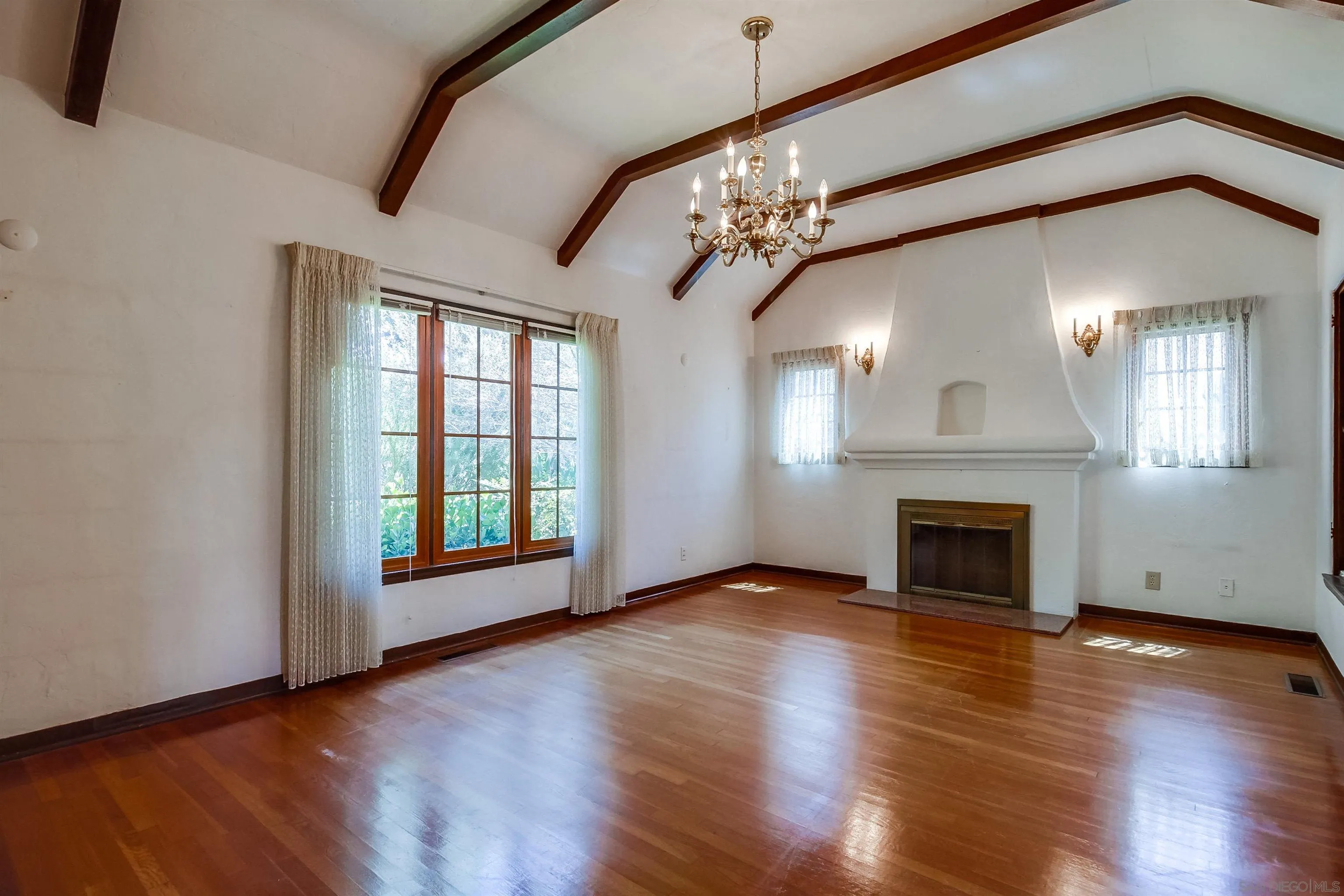 340 B Avenue Coronado, CA 92118 - Photo 7 of 31 an empty room with wooden floor a chandelier and fireplace