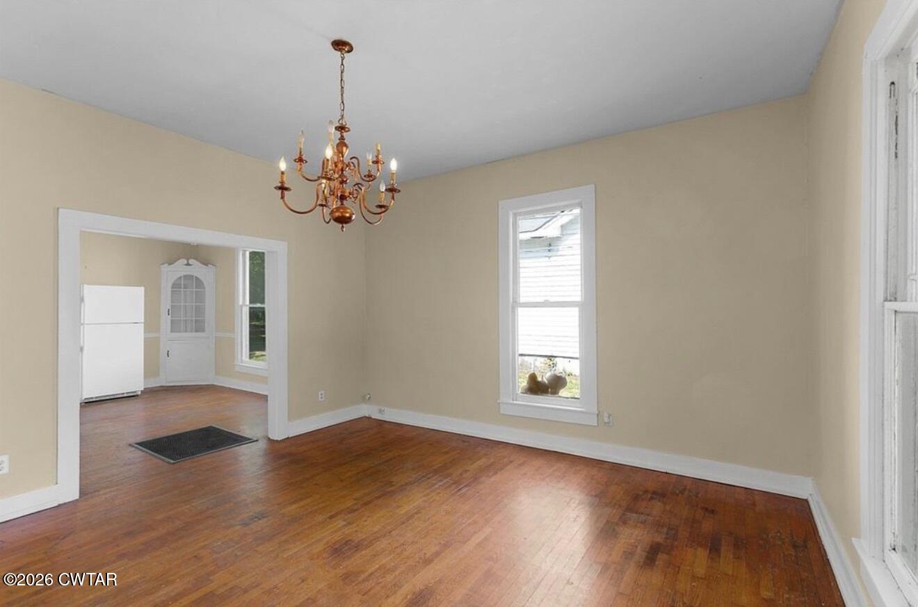125 Williams Street Jackson, TN 38301 - Photo 7 of 17 an empty room with wooden floor chandelier and windows