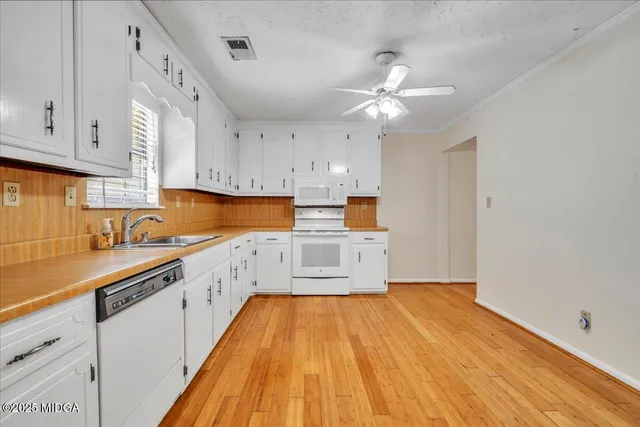 a kitchen with wooden floors and white cabinets