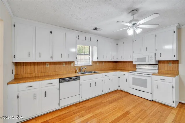 a kitchen with white cabinets and sink