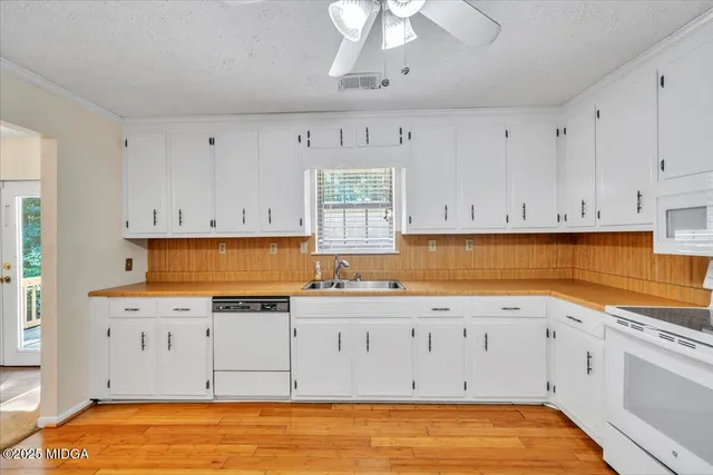 a kitchen with stainless steel appliances granite countertop a stove a sink and white cabinets