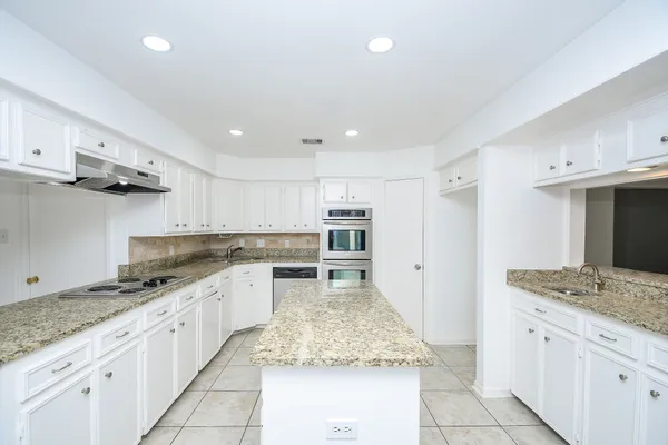 a large kitchen with granite countertop lots of counter space and wooden floor