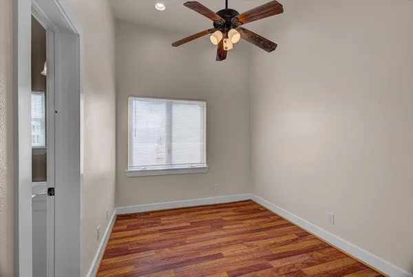 an empty room with wooden floor closet and fan