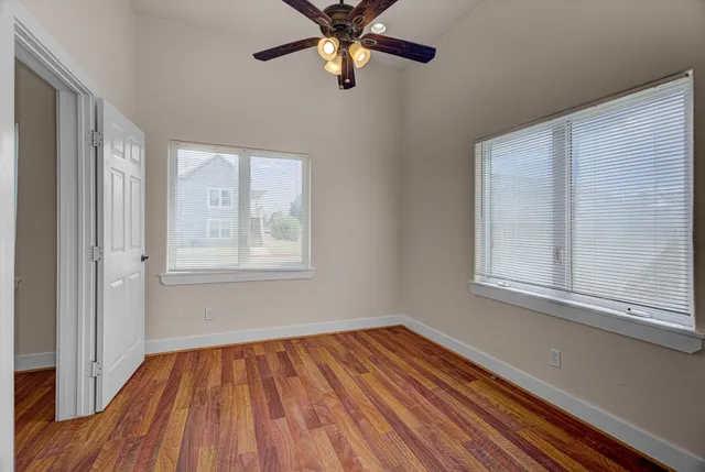 a view of empty room with wooden floor and fan