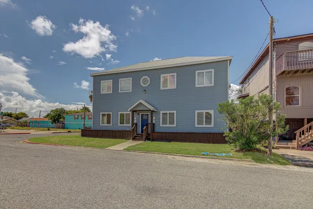 a front view of a house with a yard and potted plants