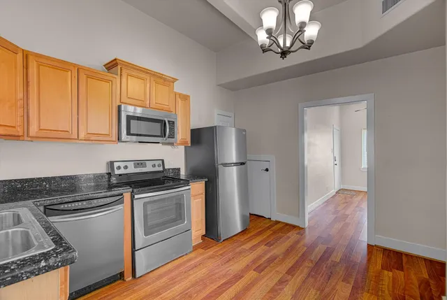 a kitchen with stainless steel appliances granite countertop a sink a stove a refrigerator cabinets and wooden floor