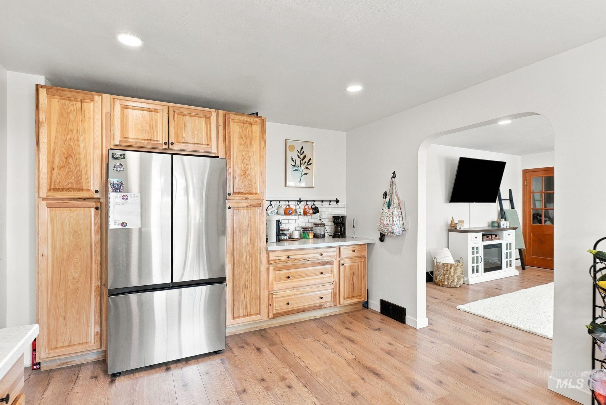 16078 Hoffman Road Kendrick, ID 83537 - Photo 14 of 47 Light wood-finish flooring, natural wood cabinetry, stainless steel refrigerator, white subway tile backsplash, and recessed lighting