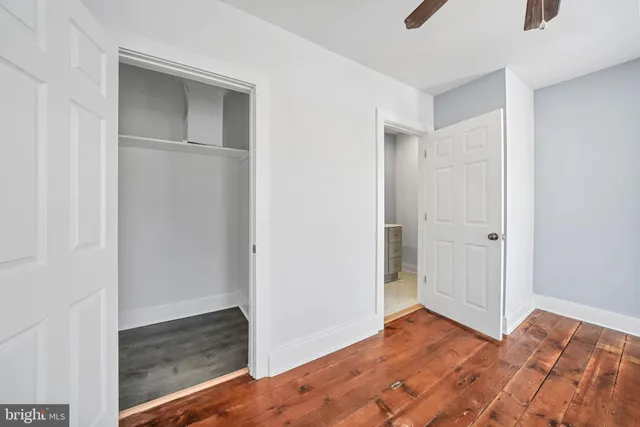 a view of a room that has a bed and wooden floor
