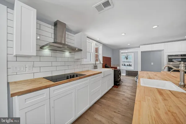 a large kitchen with stainless steel appliances a large counter top a stove a chimney a sink and a refrigerator