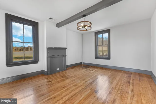 a view of an empty room with a window and wooden floor