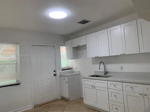 a kitchen with white cabinets and sink