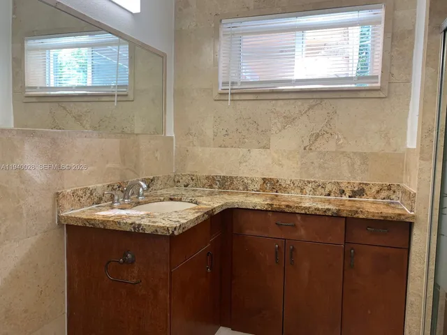 a bathroom with a granite countertop sink a window and a mirror