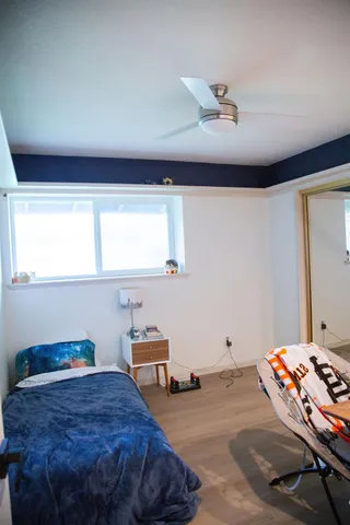 an empty room with wooden floor fan and windows