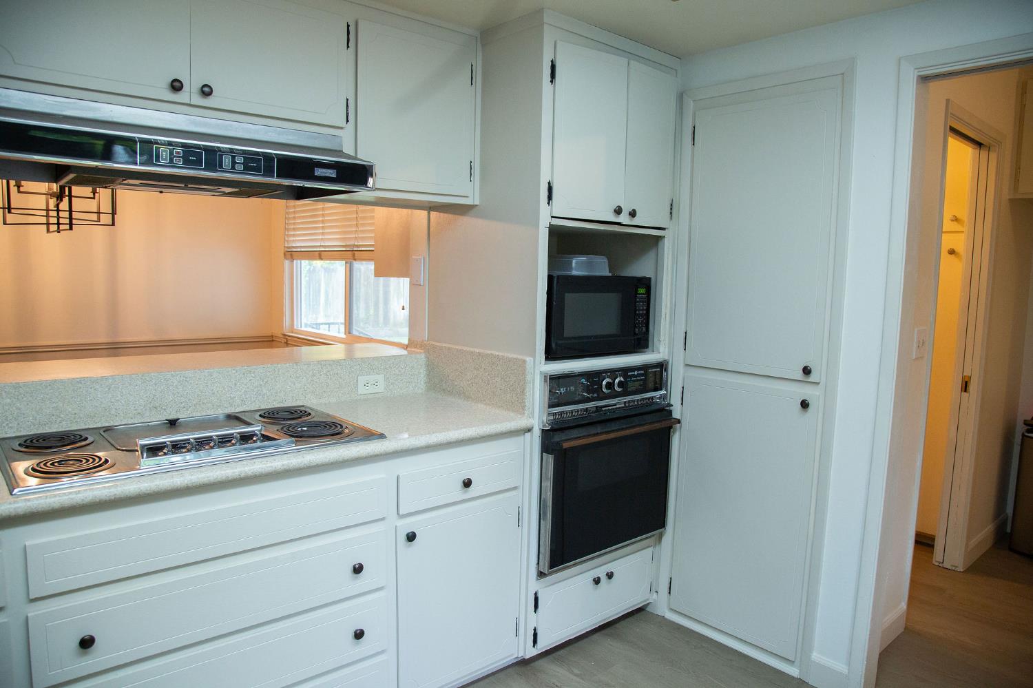 1208 Bristol Court Modesto, CA 95350 - Photo 10 of 40 kitchen with light countertops, white cabinets, black appliances,, and under cabinet range hood