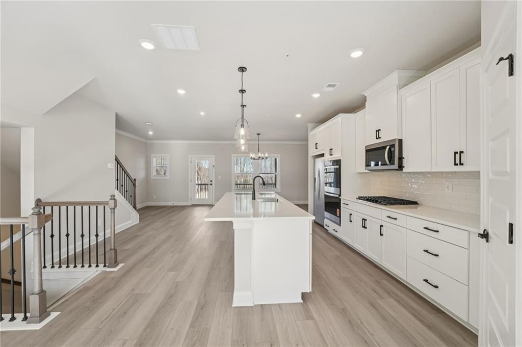 6440 Pinin Place Cumming, GA 30041 - Photo 22 of 52 a large white kitchen with wooden floor and stainless steel appliances