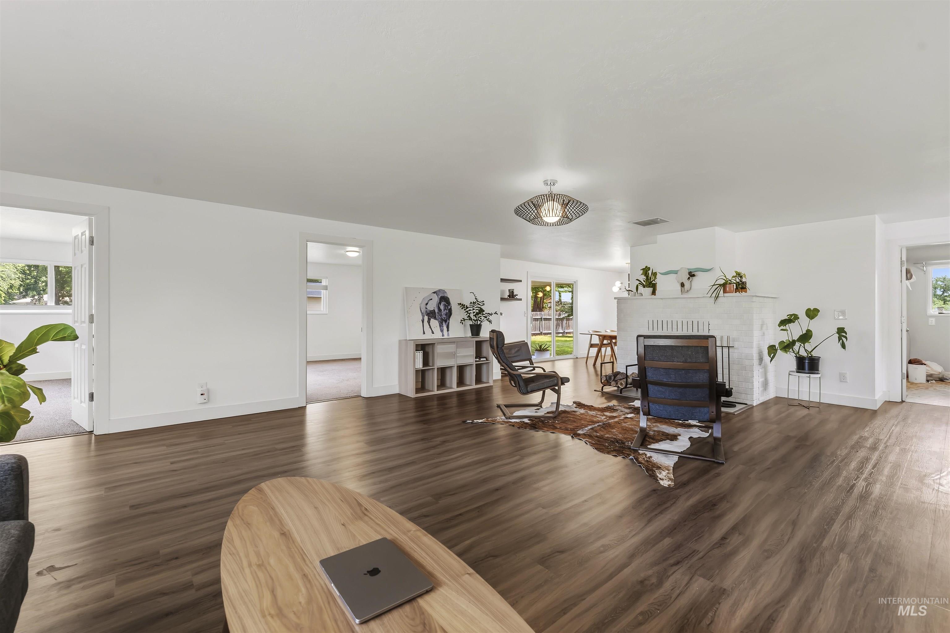 355 East Beacon Light Road Eagle, ID 83616 - Photo 6 of 47 Expansive living area featuring wood-finish flooring, white walls, and a prominent fireplace with a decorative mantel