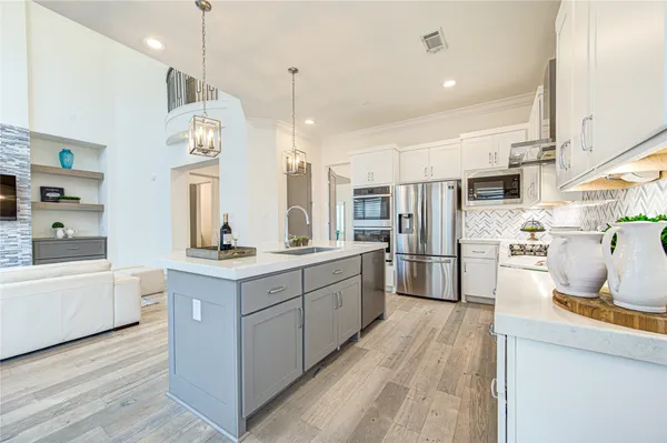a kitchen with kitchen island granite countertop a sink cabinets and stainless steel appliances