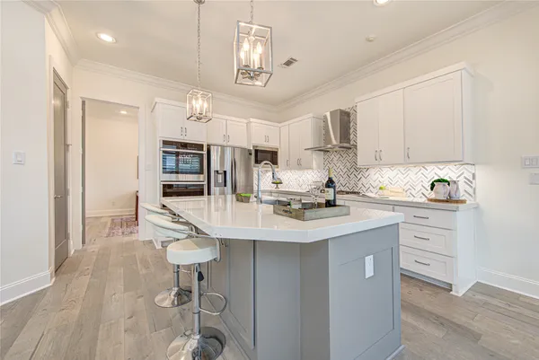 a kitchen with stainless steel appliances granite countertop a refrigerator a sink dishwasher and white cabinets with wooden floor