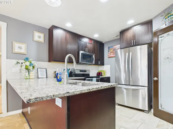 a kitchen with granite countertop stainless steel appliances a refrigerator a sink a stove a microwave and island