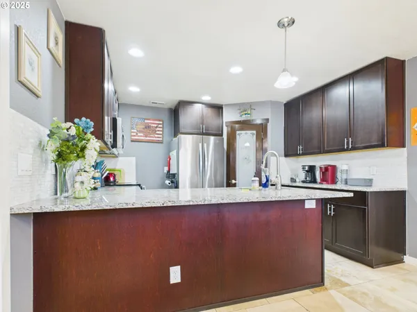 a view of a kitchen with kitchen island a counter top space appliances cabinets and a potted plant