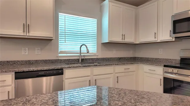 a kitchen with granite countertop white cabinets stainless steel appliances and a sink