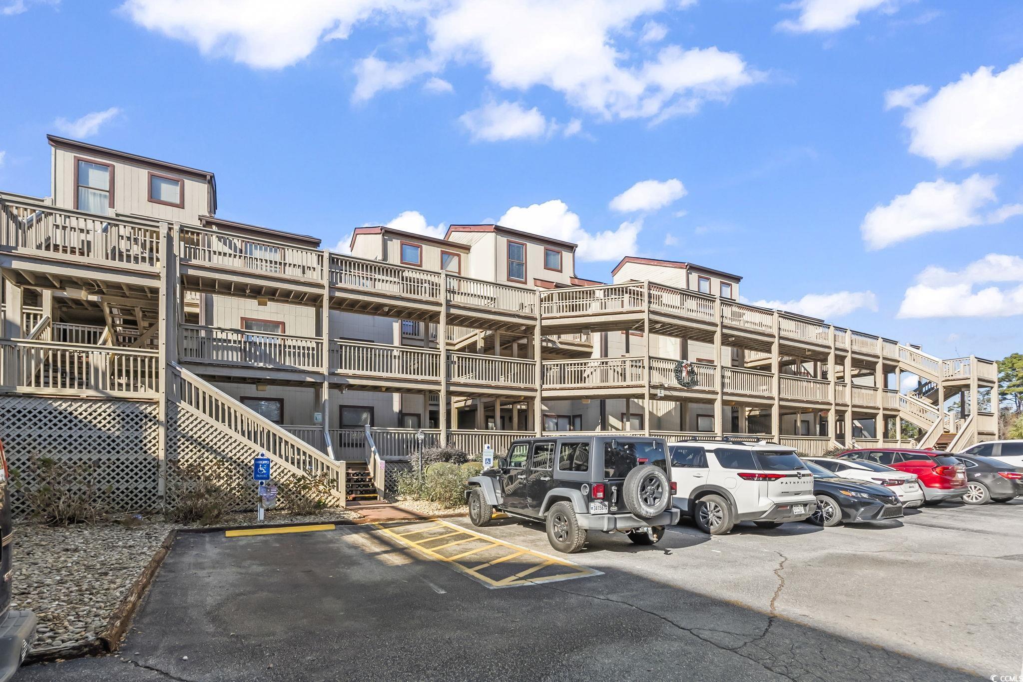 View of apartment building / complex featuring uncovered parking and stairs