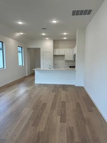 a view of a kitchen with kitchen island a sink wooden floor and a refrigerator