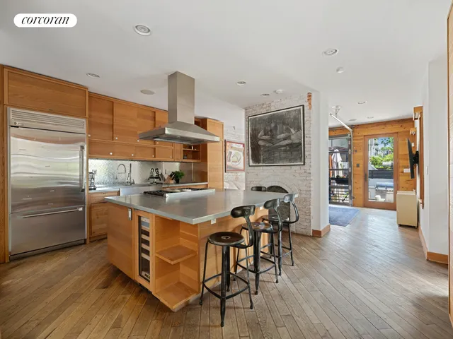 a living room with stainless steel appliances kitchen island granite countertop a couch and a flat screen tv