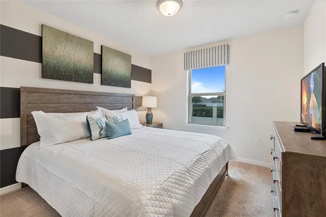 a bedroom with a bed and a flat tv screen on a dresser