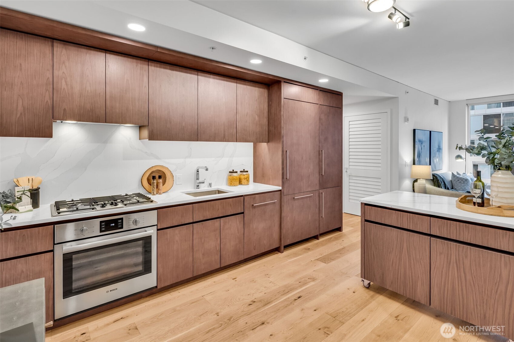 121 Stewart Street, Unit 1003 Seattle, WA 98101 - Photo 13 of 40 a kitchen with kitchen island granite countertop wooden cabinets and white appliances