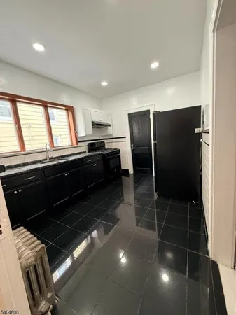 a kitchen with granite countertop a refrigerator and a stove top oven