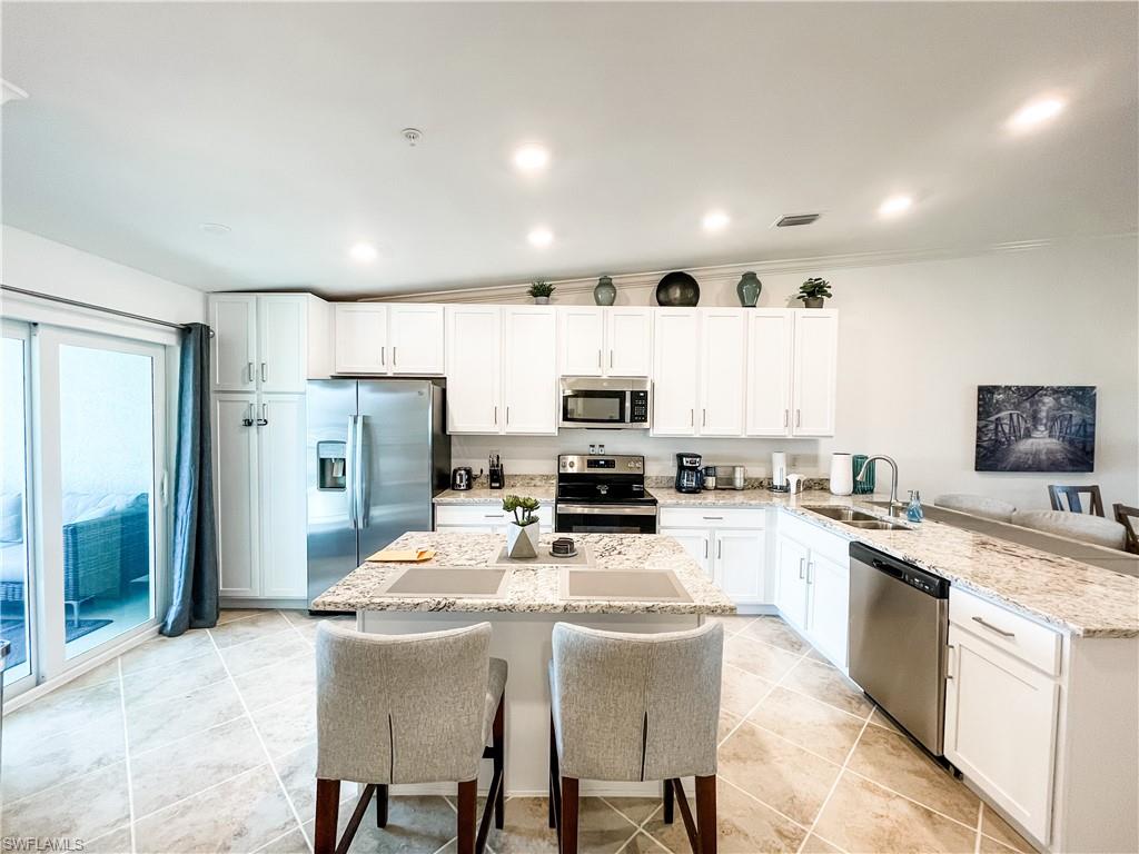 16000 Grassland Lane, Unit 3127 Babcock Ranch, FL 33982 - Photo 9 of 44 a kitchen with stainless steel appliances kitchen island granite countertop a stove top oven a sink a refrigerator with a dining table and chairs