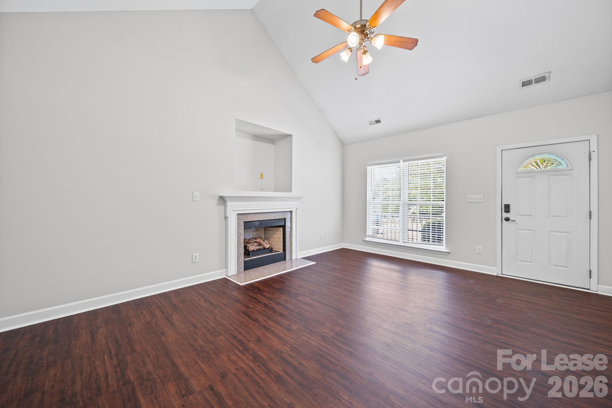 1728 Brian William Road Charlotte, NC 28212 - Photo 2 of 15 an empty room with wooden floor chandelier fan and windows
