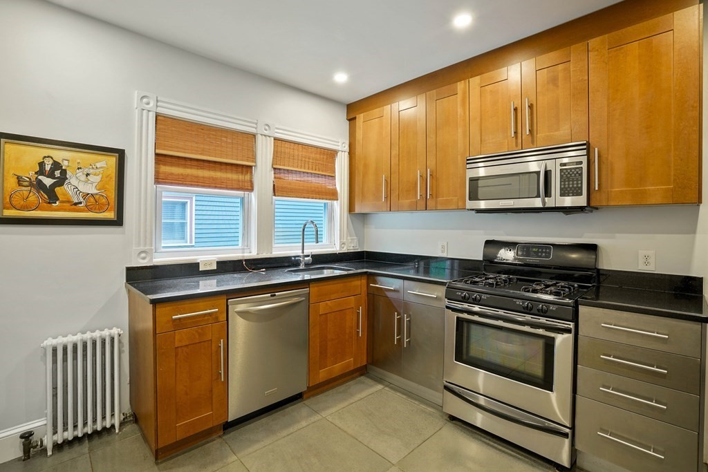 23 Stetson Street, Unit ONE Brookline, MA 02446 - Photo 6 of 15 a kitchen with stainless steel appliances granite countertop wooden cabinets stove and a sink