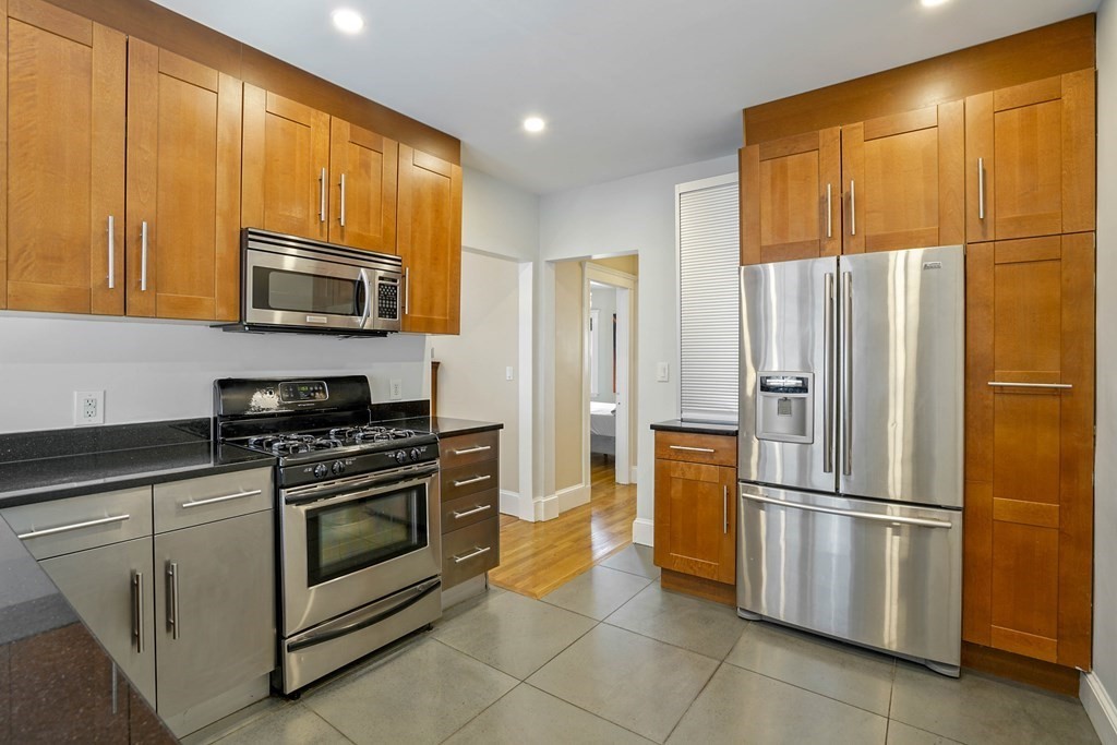 23 Stetson Street, Unit ONE Brookline, MA 02446 - Photo 7 of 15 a kitchen with stainless steel appliances granite countertop a refrigerator stove and microwave