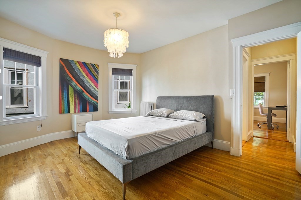 23 Stetson Street, Unit ONE Brookline, MA 02446 - Photo 8 of 15 a spacious bedroom with a bed and a chandelier